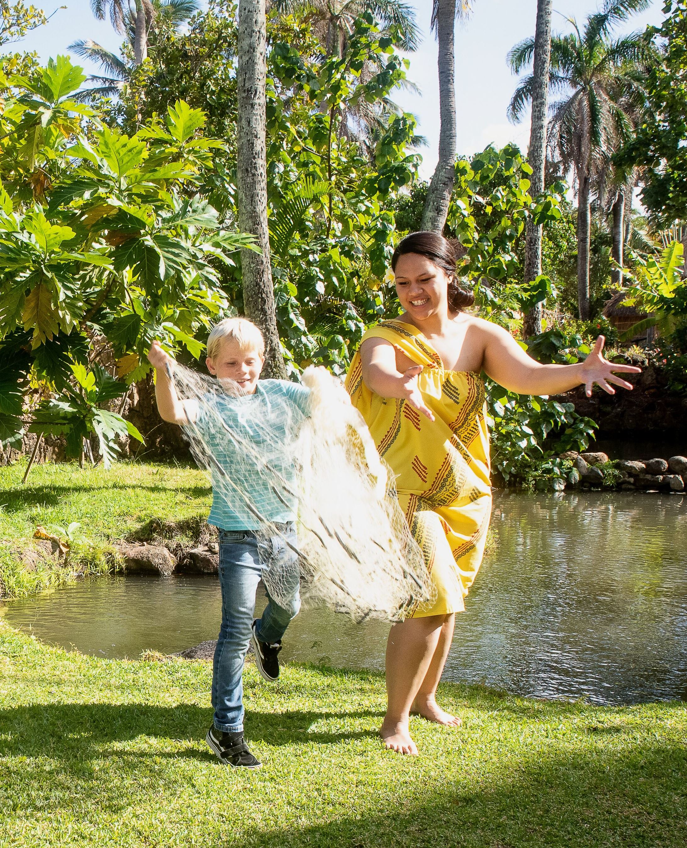 Picture of boy tossing a fishing net in the Hawaiian Village at the Polynesian Cultural Center