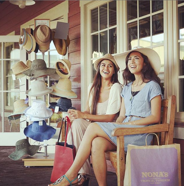 Two women shopping at the Hukilau Marketplace. The store pictured is Nona's Tropical Threads.
