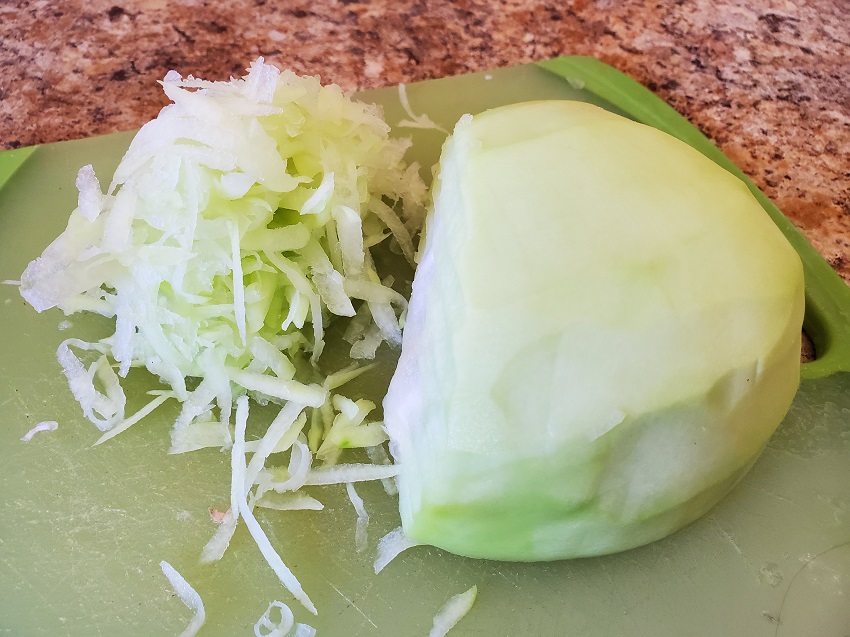 photo of a green papaya peeled and seeded with some grated papaya