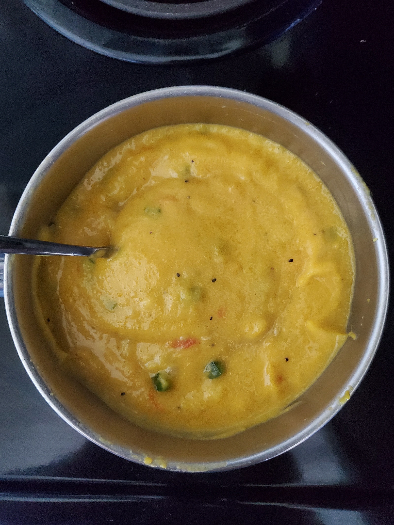 Picture of pumpkin soup made with coconut milk and optional ingredients in a metal saucepan.