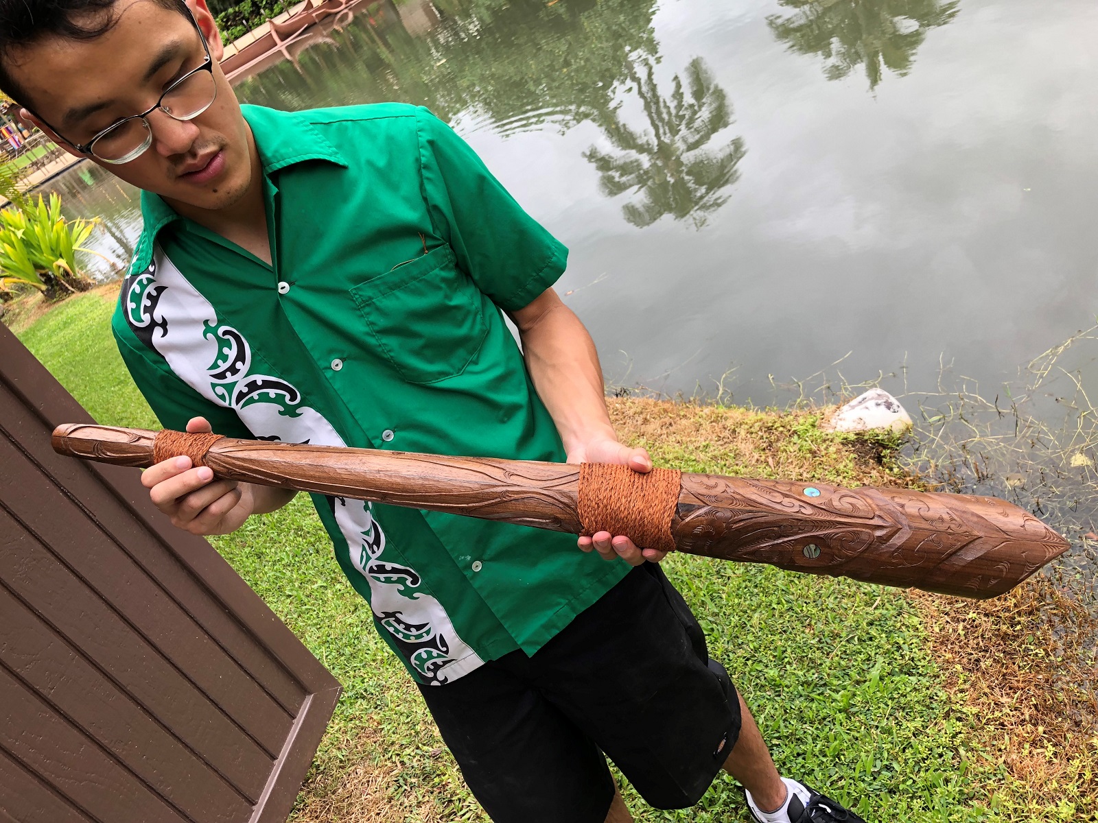 photo of Sam Ho Ching student carver at the Polynesian Cultural Center displaying a Polynesian inspired weapon
