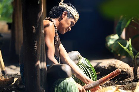 Samoan man starting fire with two hibiscus sticks and coconut husks at the Polynesian Cultural Center - Exclusive ticketing available January and February 2021.