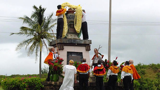 photograph of Prince Kuhio celebration where Hawaiians honor the Prince by laying massive fresh flower leis on a monument honoring his birth.. photo courtesy of Aloha-Hawaii