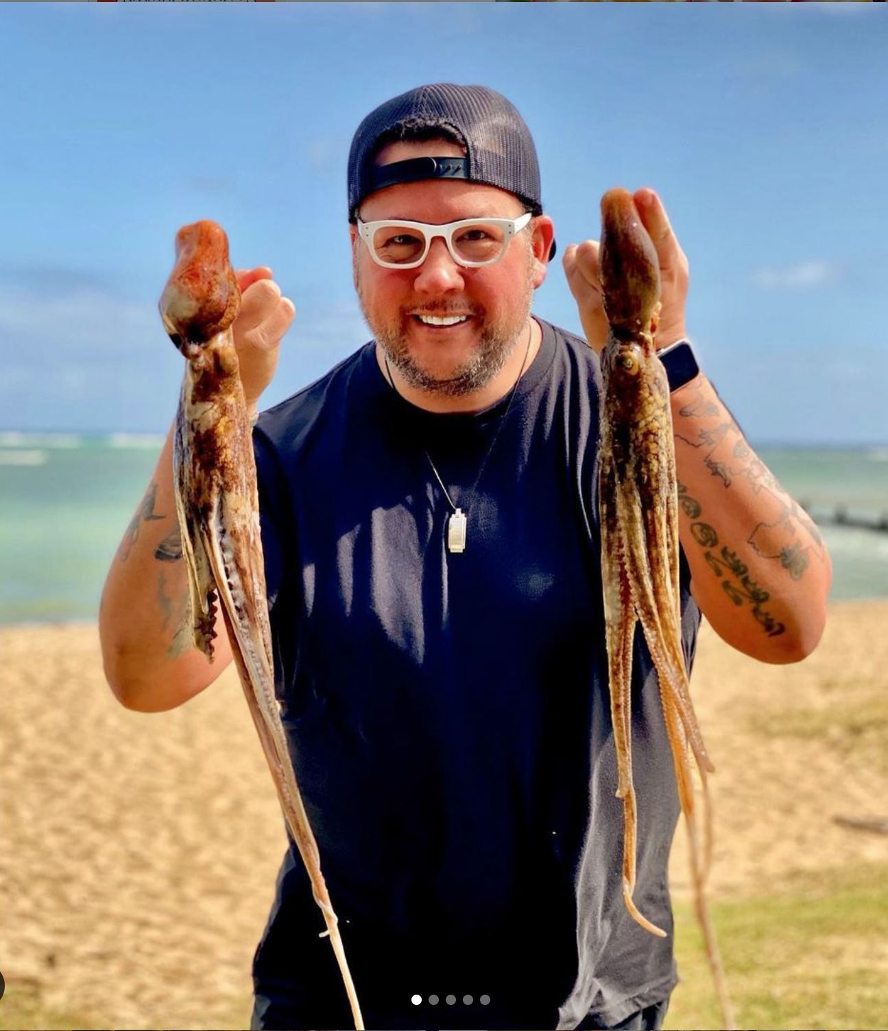 image of Chef Graham Elliot holding two squid along the Hawaii shoreline