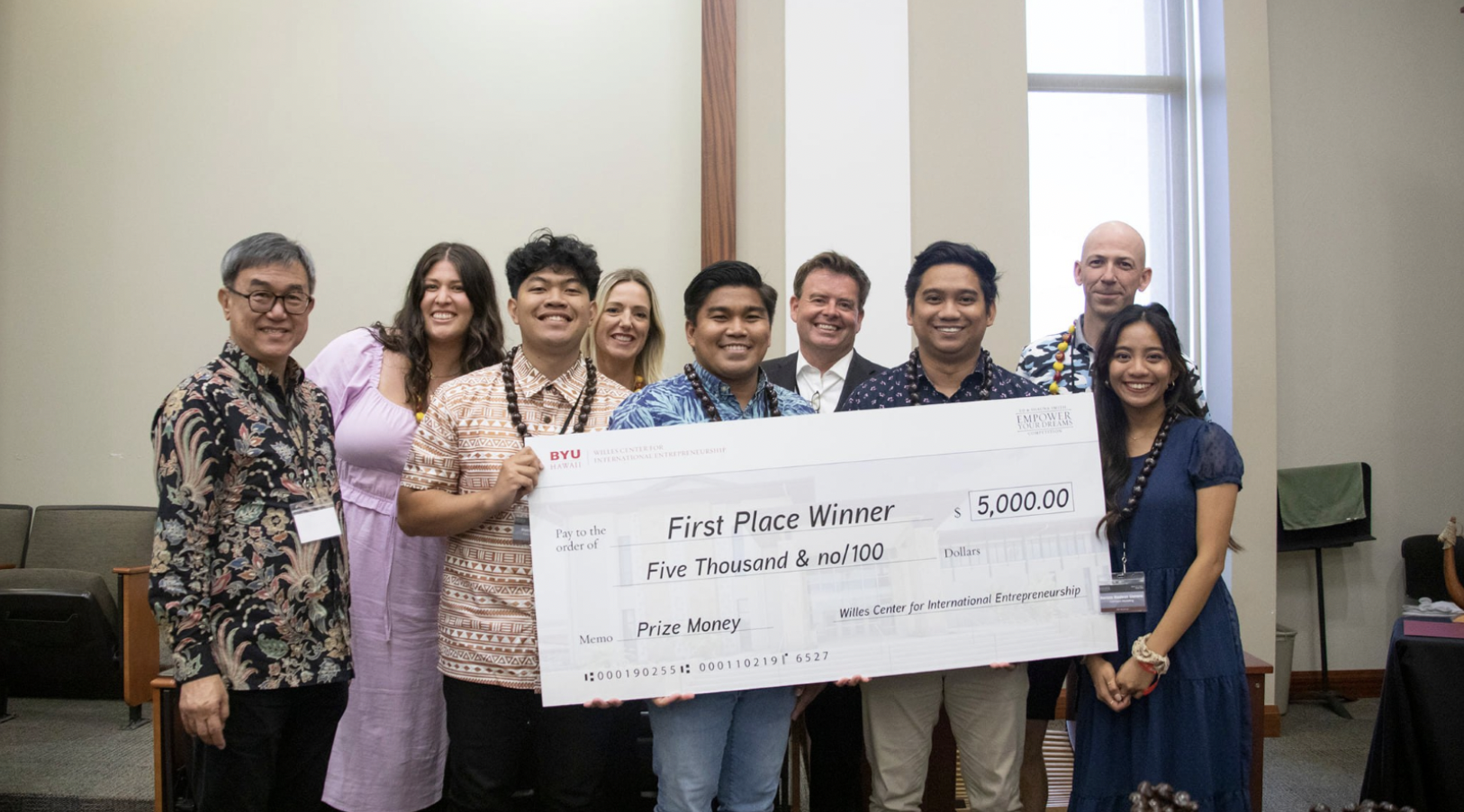 Photo of the winners holding the cash prize check amounting to $5,000. Behind stood the four distinguished judges of the 22 Empower Your Dreams Competition with Dr. Jason Earl, the Academic Director of the Entrepreneurship Program at Brigham Young University-Hawaii.