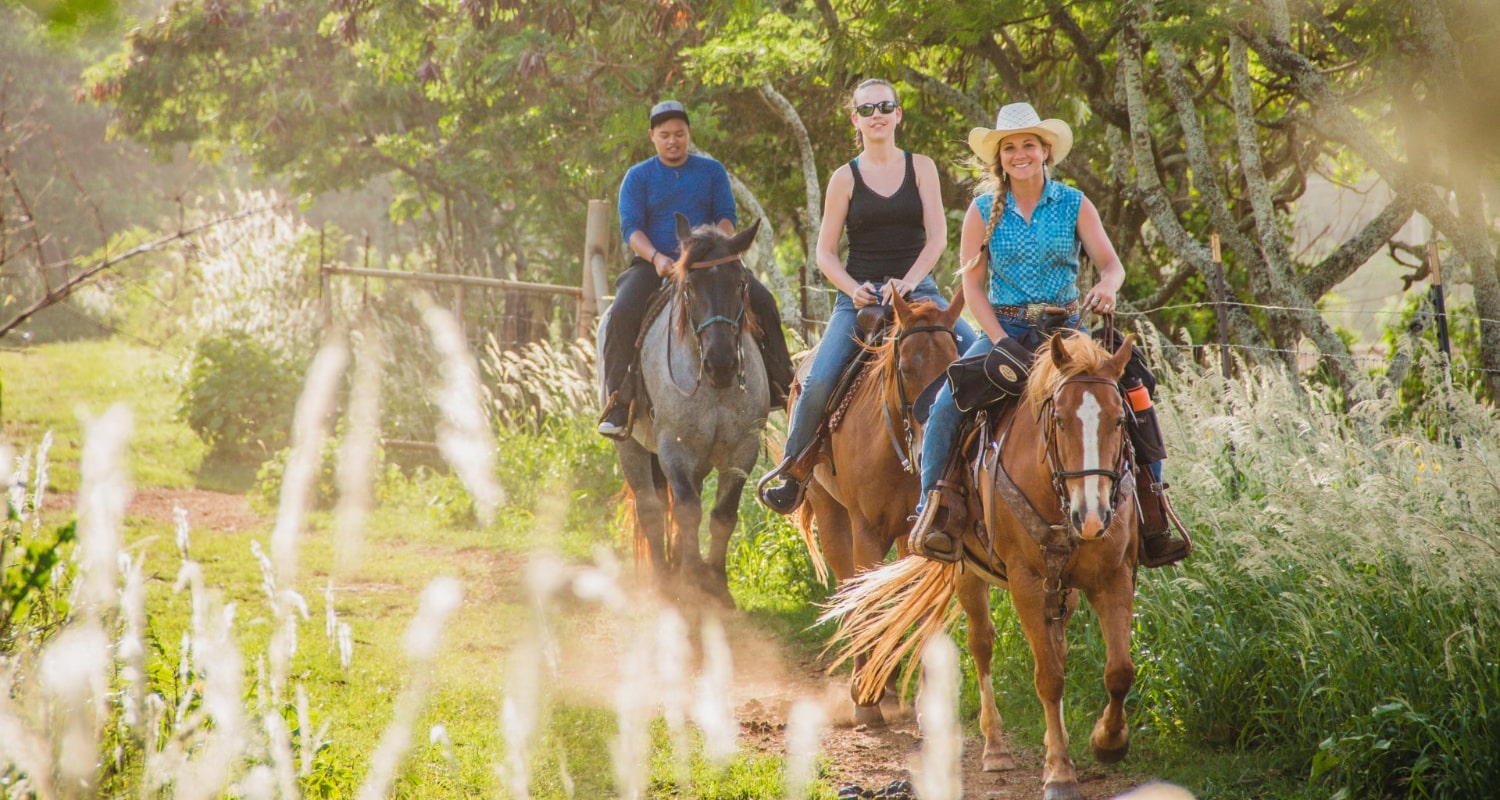 Two ladies and a guy horsebackriding.