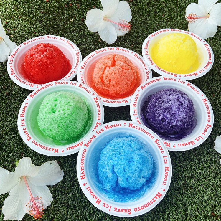 Six different flavors of shave ice in bowls.