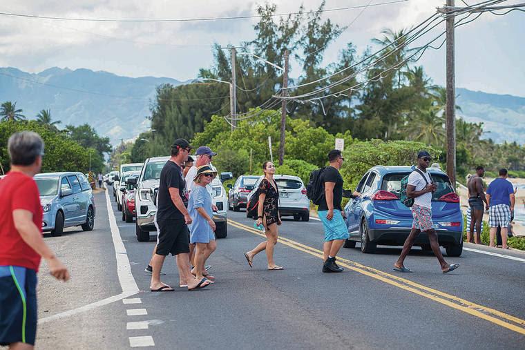 photo of people crossing in the middle of traffic. Traffic jam on the North Shore of Oahu, Hawaii.. Credit Star Advertiser.