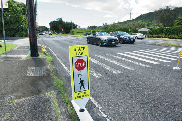 photo of pedestrian crosswalk sign indicates STOP to the incoming vehicles on Pali Highway in Oahu, Hawaii. Mahalo i ka ʻāina is how to respect the locals.