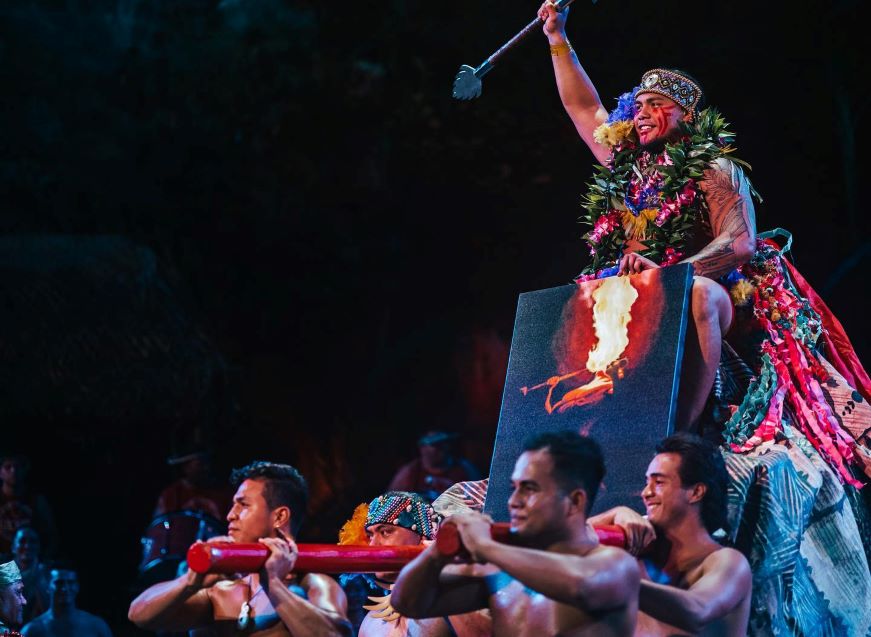 The winner of this year’s World Fireknife Championship, Hale Motuapuaka, sits atop his throne as members of HA: Breath of Life show present him to the packed theatre audience.