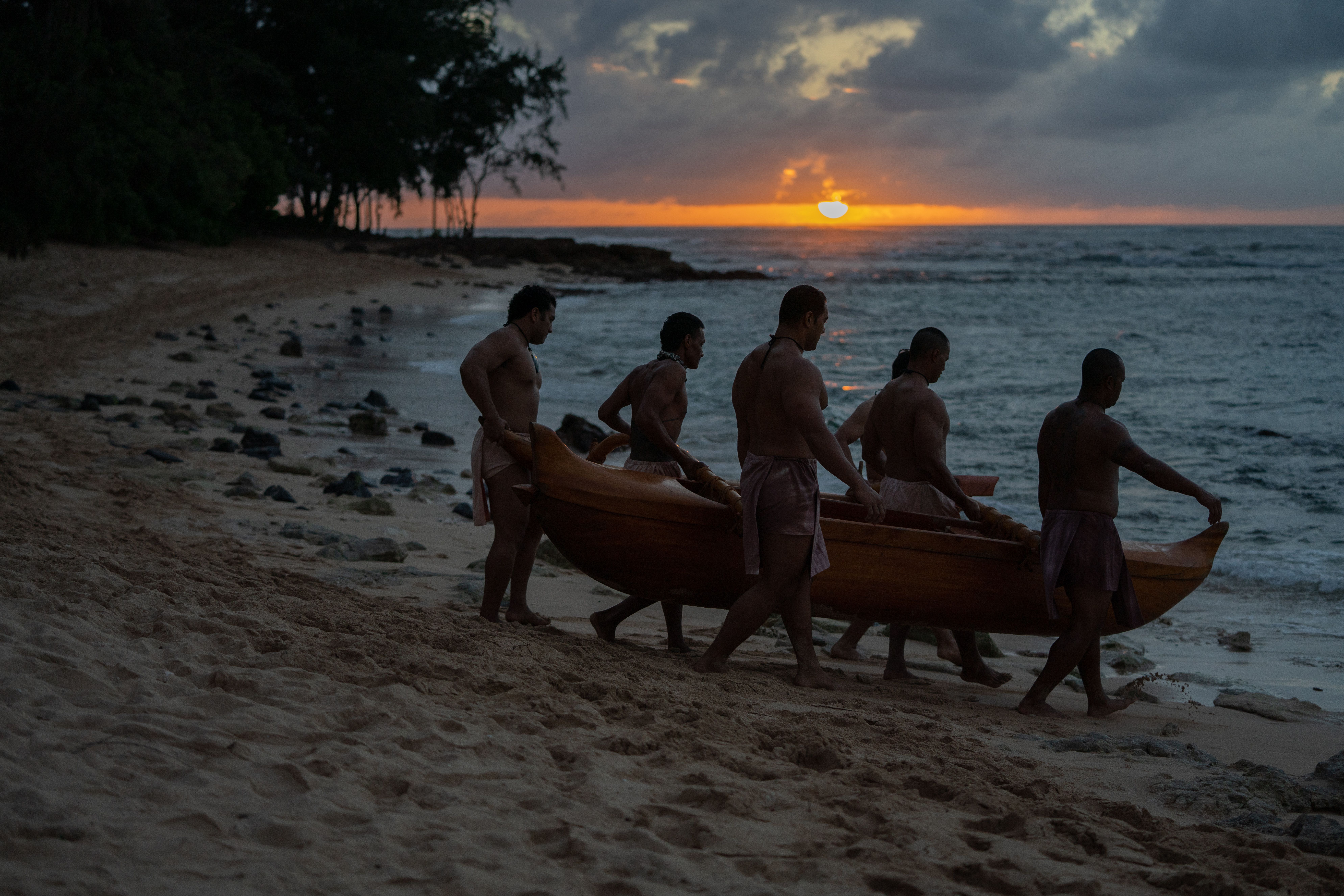 Mahalo i ka aina lead image. Photo of men and canoe at the beach in Laie, Oahu, Hawaii.