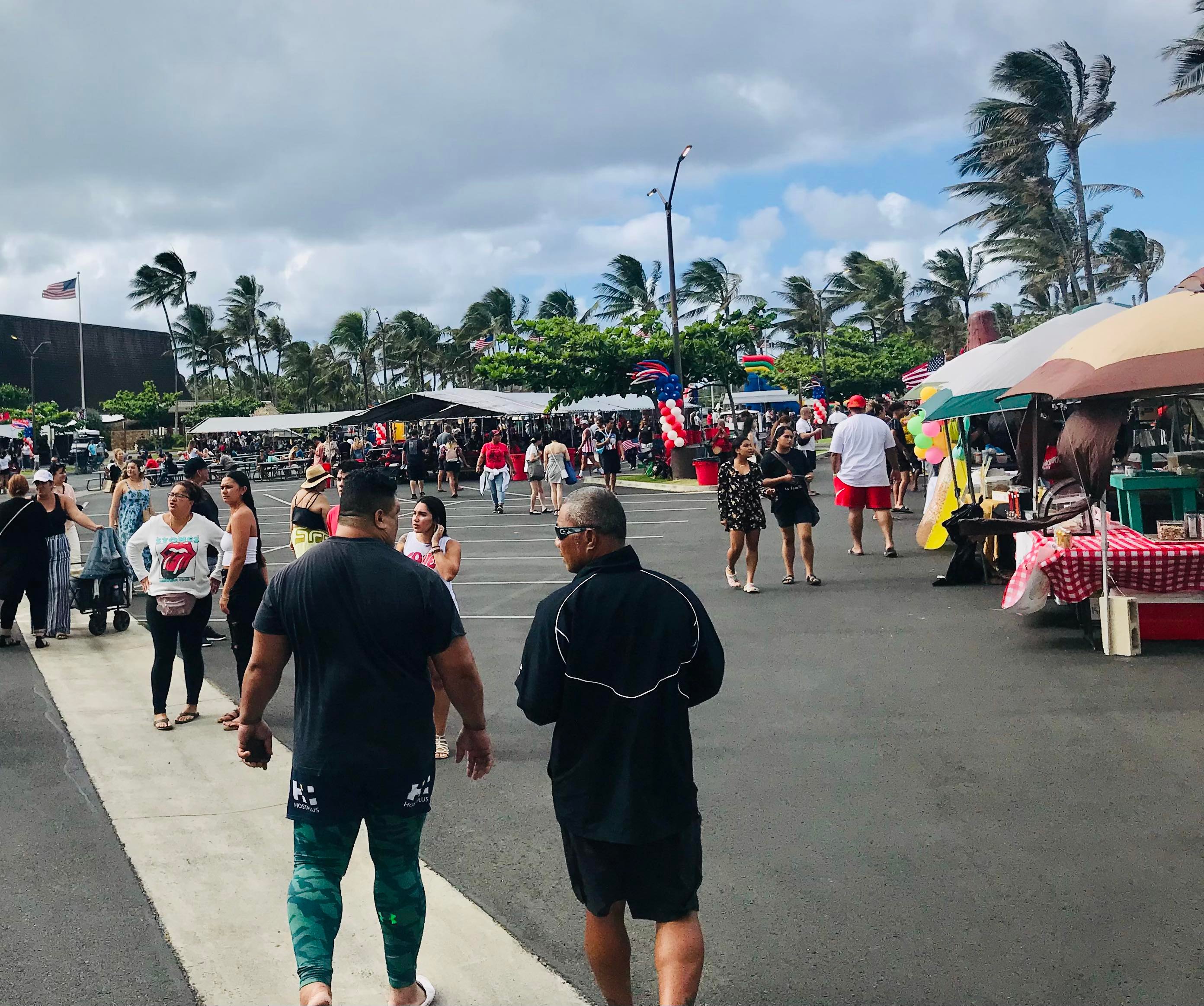 Photo of multiple food vendors lined up around the Center parking lot. People are walking and looking around to buy their favorite food to enjoy on the 4th of July.