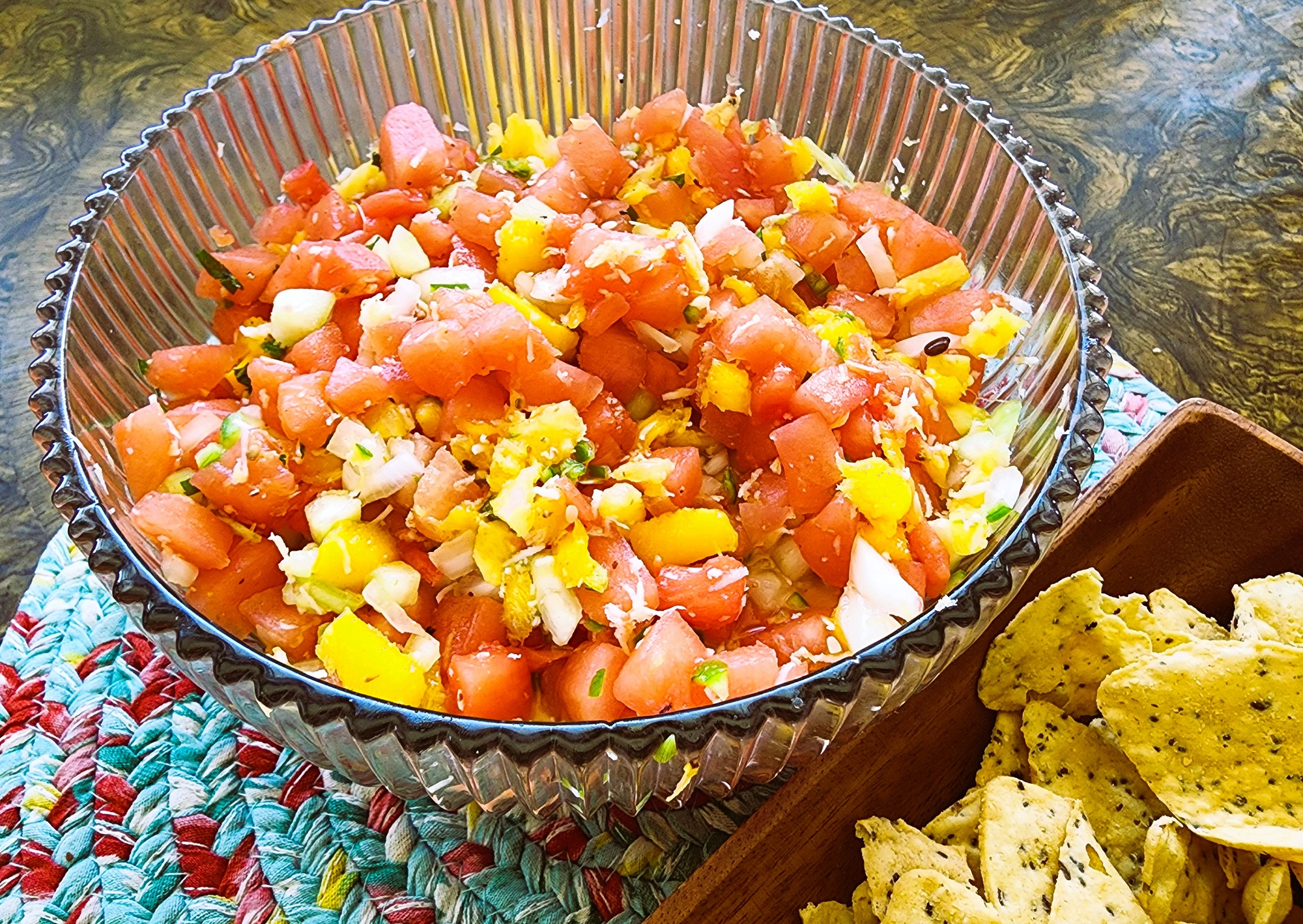 watermelon, pineapple, mango, shredded coconut, lime juice, cucumber, onion, spicy pepper chopped and added to a glass bowl with tortilla chips