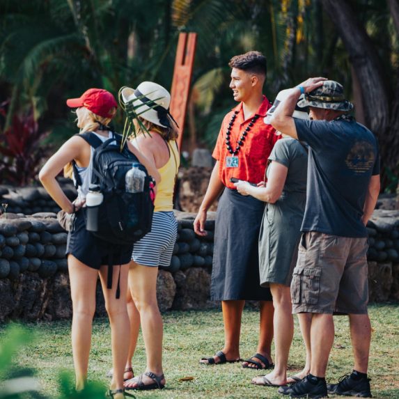 photograph showing a Polynesian guide providing a guided tour of the Polynesian Cultural Center to four guests