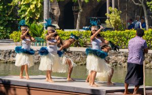 Tahitian dancers showcase their traditional attire and dance on a canoe.