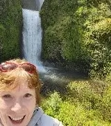 Peggy in the corner of the shot, with a big smile. Beautiful waterfall behind her