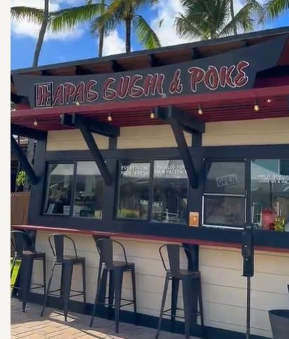 Hapas Sushi & Poke serving window and bar stools. Red and black against beige wall.