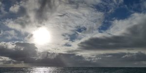 Sun behind clouds on a stormy morning over the sea