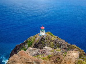 A lighthouse on the edge of the cliff overlooking the ocean.