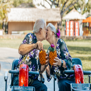 Senior couple on scooters, enjoying a kiss and pineapple drinks